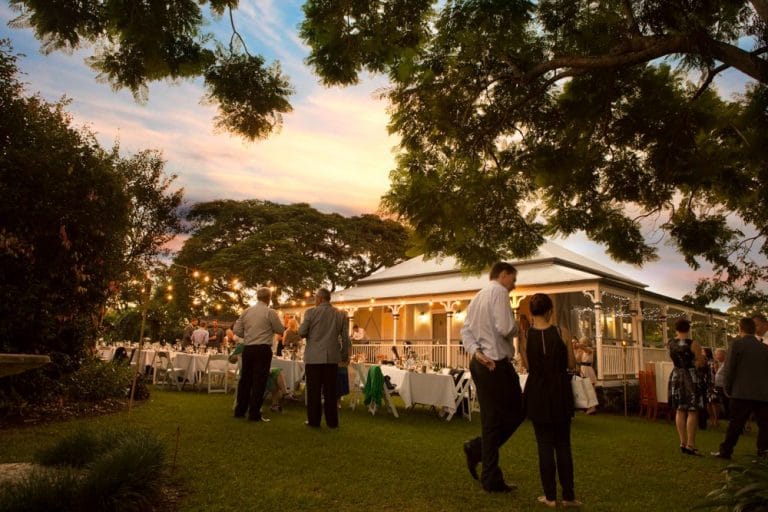 Guests gathered on the lawn at dusk in front of the lit-up cottage