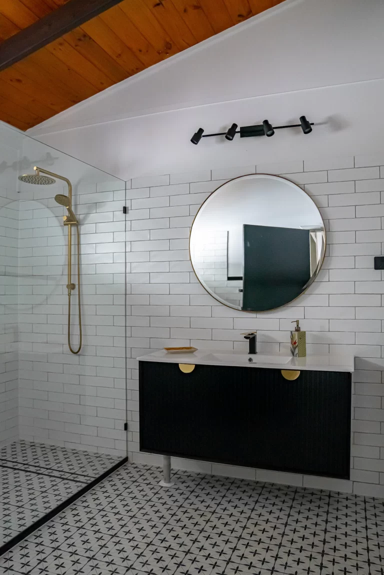 The bathroom with a round mirror and black tapware