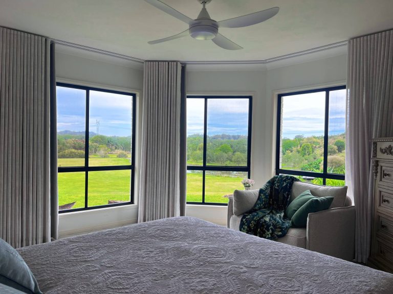 A queen bedroom at Peachester Villa with bay windows looking over the lawns
