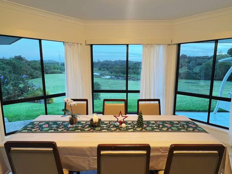 The dining table at Peachester Villa with floor-to-ceiling windows over the lawns